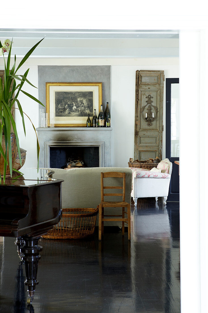 Comfortable country-house ambiance with sofa set in front of fireplace and classic grand piano on polished, black wooden floor