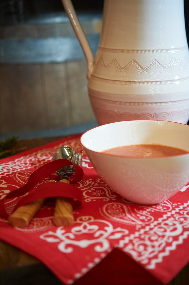 Tomatensuppe auf einem rot-weiss gemusterten Tuch mit Gabel und Löffel