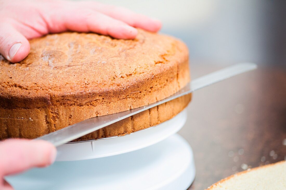 A sponge cake being sliced through the middle