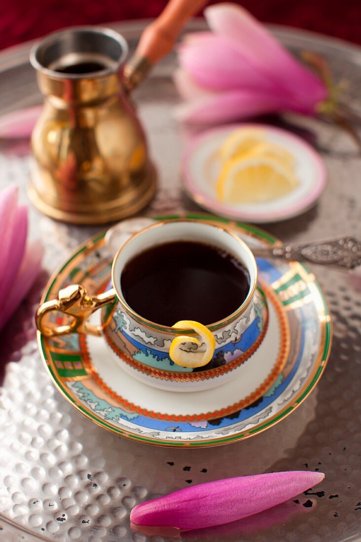 Eine Tasse Kaffee mit Blütendeko auf silbernem Tablett