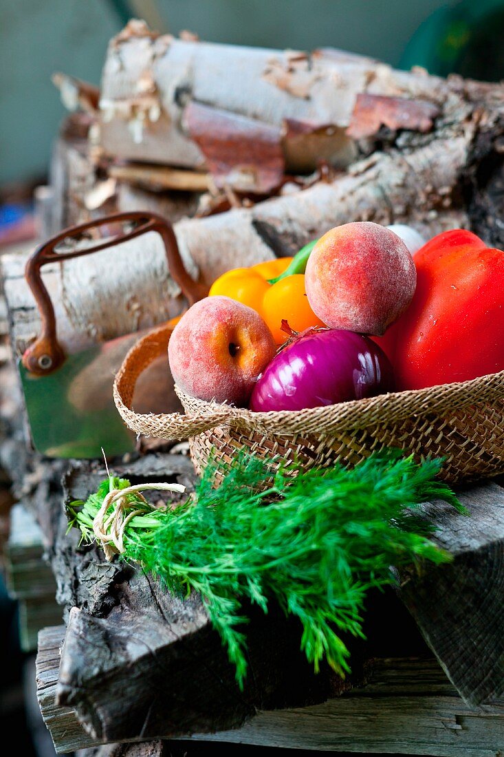 Fresh Veggies and Fruit in a Basket; Bunch of Fresh Dill; On a Woodpile