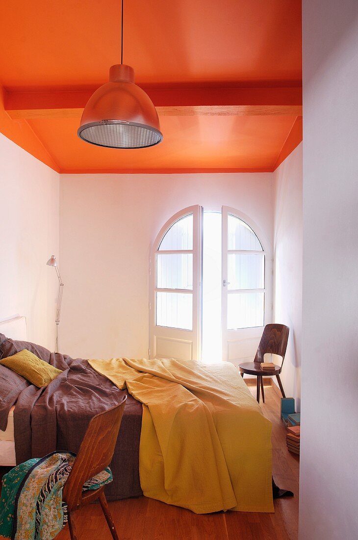 Simple industrial style in narrow bedroom with ceiling painted a bold orange