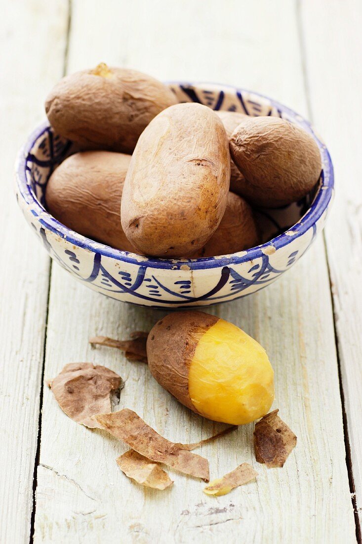 Potatoes cooked in their skins, in and next to a bowl