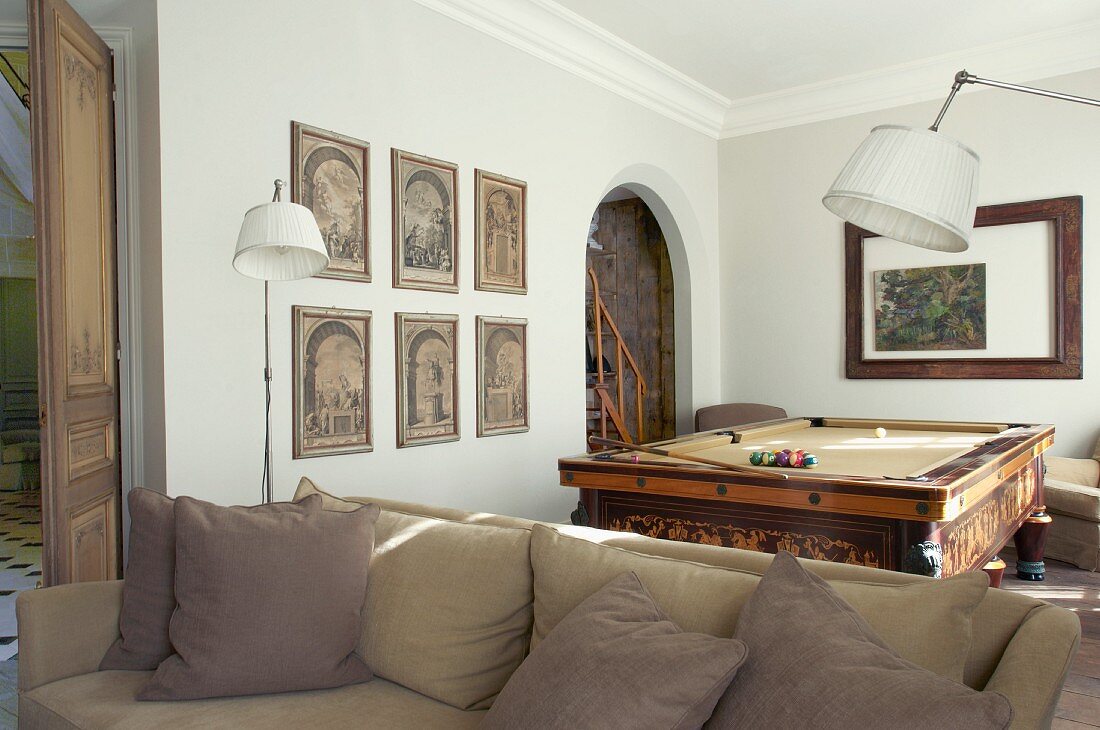 Couch in front of standard lamps and pool table in traditional lounge