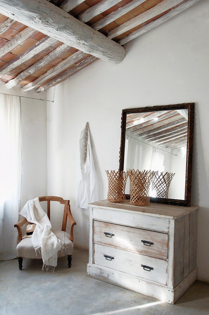 Spiegel auf Vintage Kommode und Sessel unter mediterraner Dachkonstruktion in Schlafzimmerecke