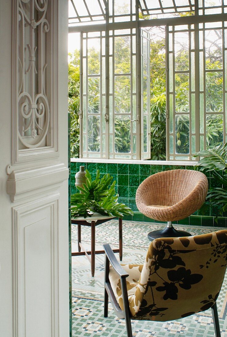 Zwei bequeme Stühle und Tisch in klassischem Wintergarten mit grünen Wandfliesen und Mosaikboden