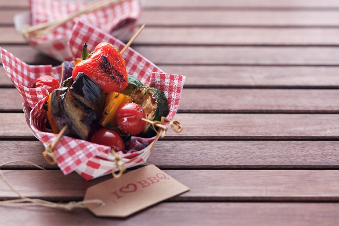 Barbecued vegetables skewers on a napkin in a cardboard container