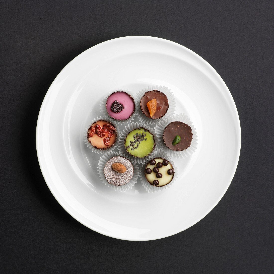 Assorted hand-made filled chocolates on a plate (view from above)