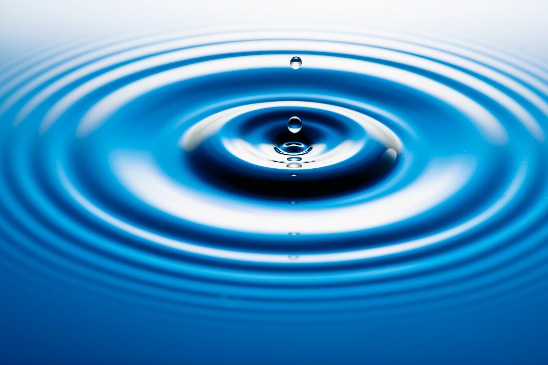A drop falling into water and forming circles on the water surface