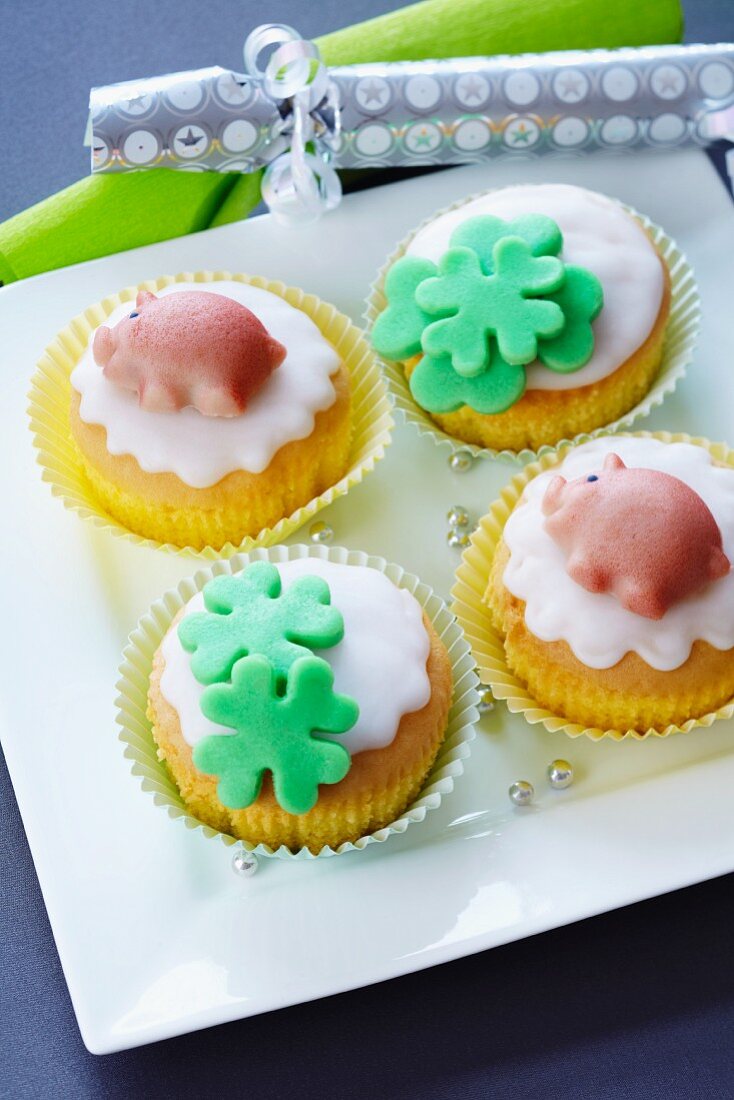 Muffins decorated with marzipan clover leaves and lucky pigs