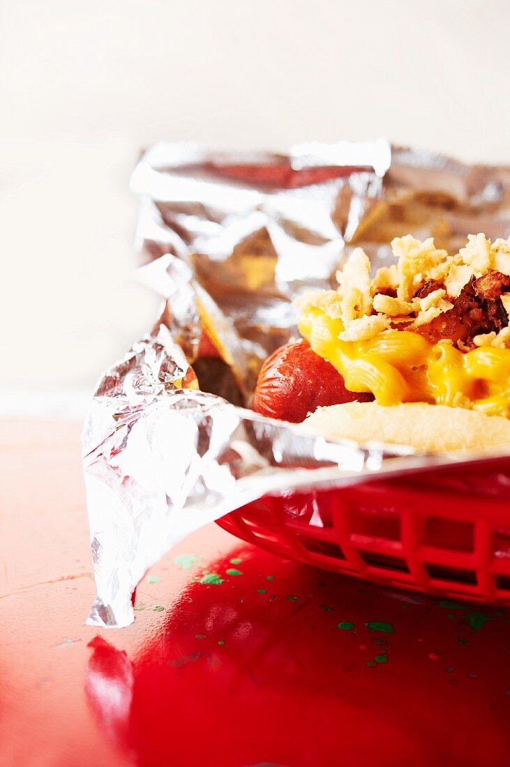 Smoked Chili Dog Topped with Cheesy Macaroni and Cheese; In a Plastic Basket