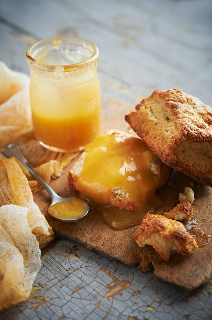 Zitronen-Buttermilch-Scones mit Lemon Curd auf einem rustikalen Holzbrett