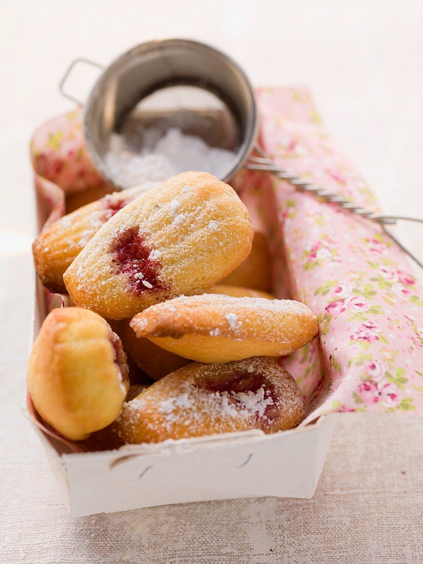Madeleines with raspberry jam and icing sugar in a bowl