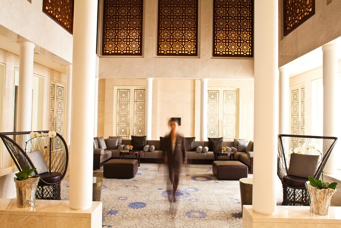 View through doorway flanked by columns in elegant foyer with lounge area