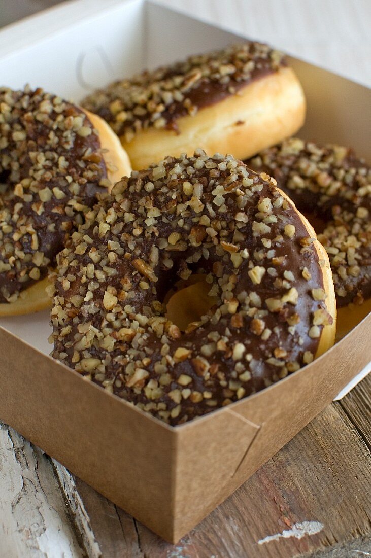 Doughnuts with chocolate glaze and chopped nuts in a box