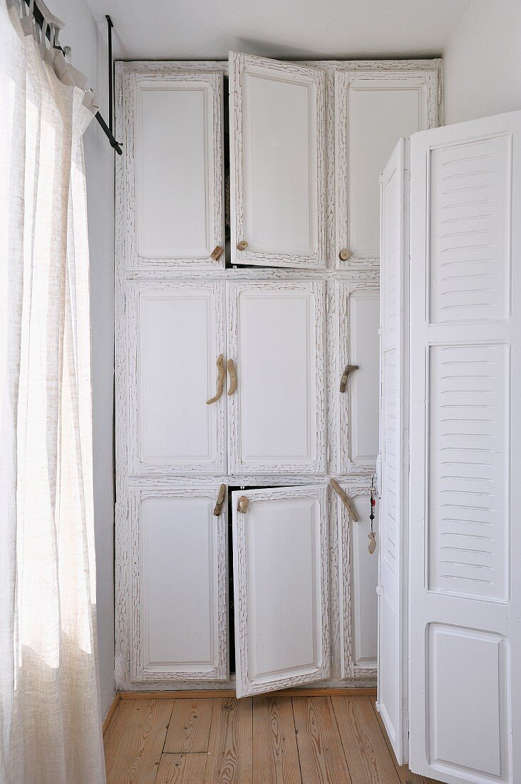 White lacque, r built in cupboard with natural wood door pulls in a narrow room