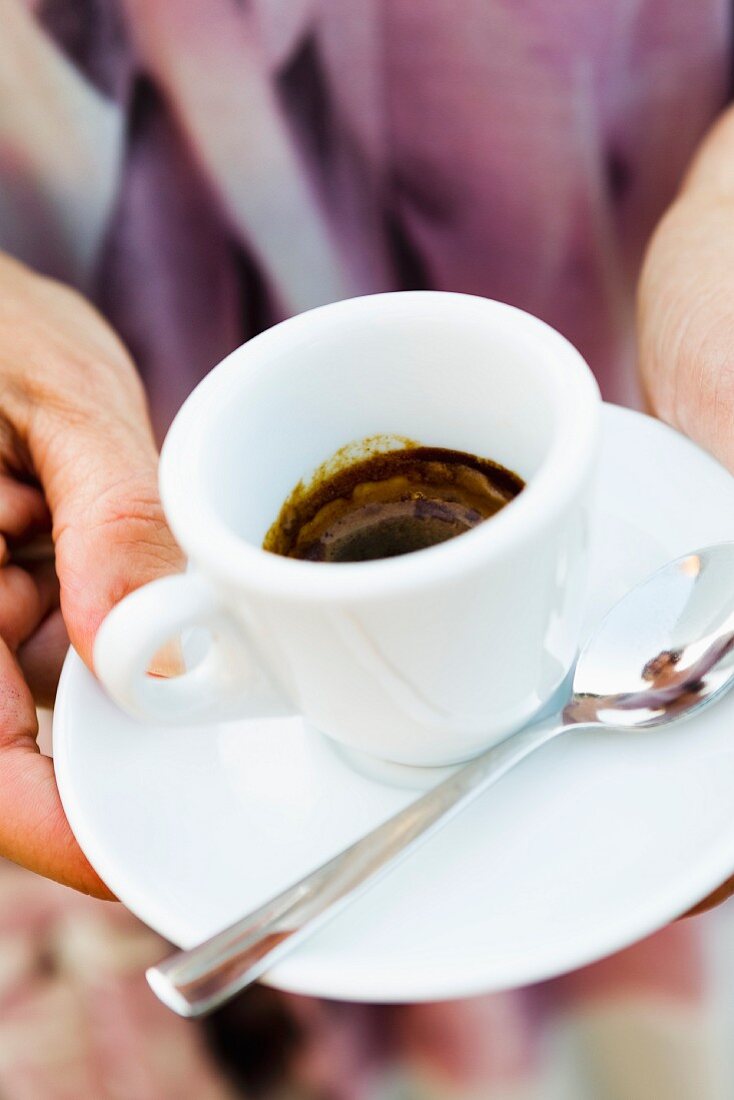 Hands holding an espresso cup