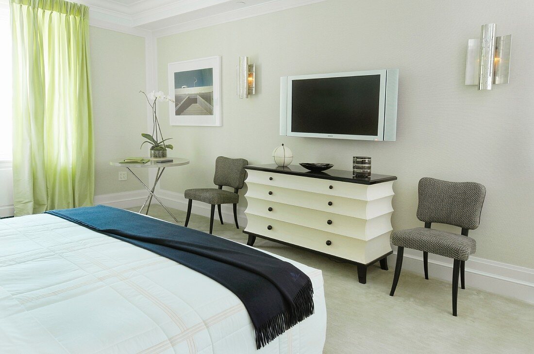 Bed room with black and white, post-modern chest of drawers between upholstered chairs