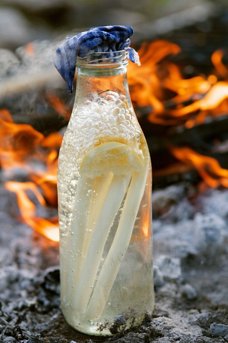 In der Flasche kochender Spargel; im Hintergrund ein offenes Feuer