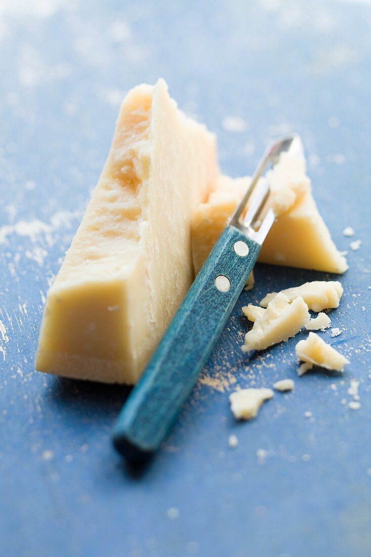 A chunk of parmesan with a cheese slicer