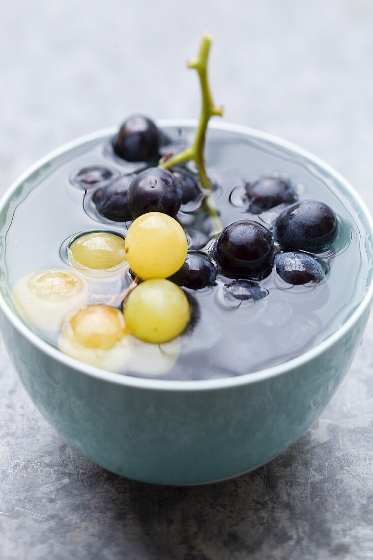Green and black grapes in a bowl of ice-cold water