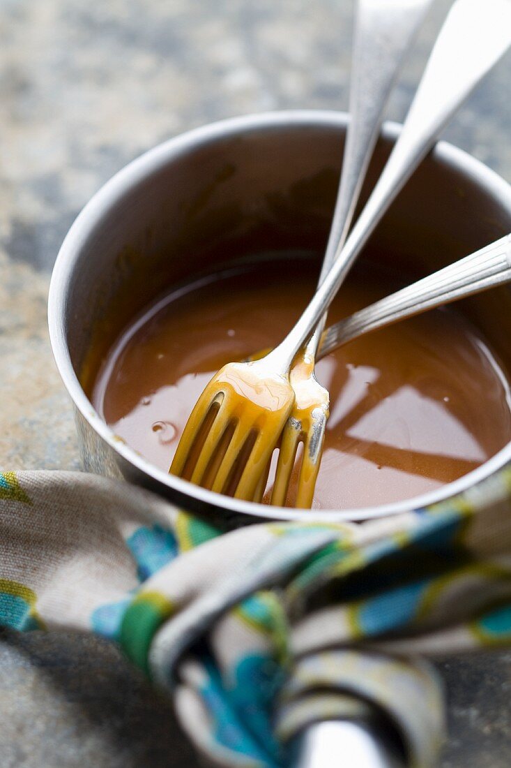 Caramel sauce in a saucepan with forks