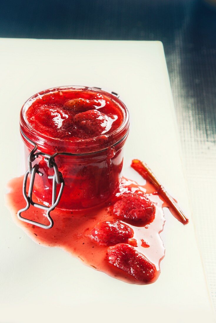 Strawberry jam in a jar; some spilt