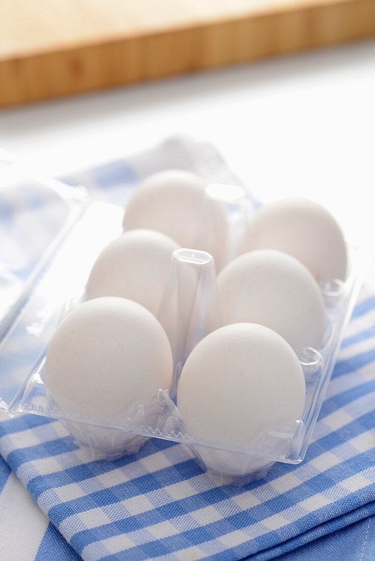 Sechs weiße Eier im Plastikbehälter