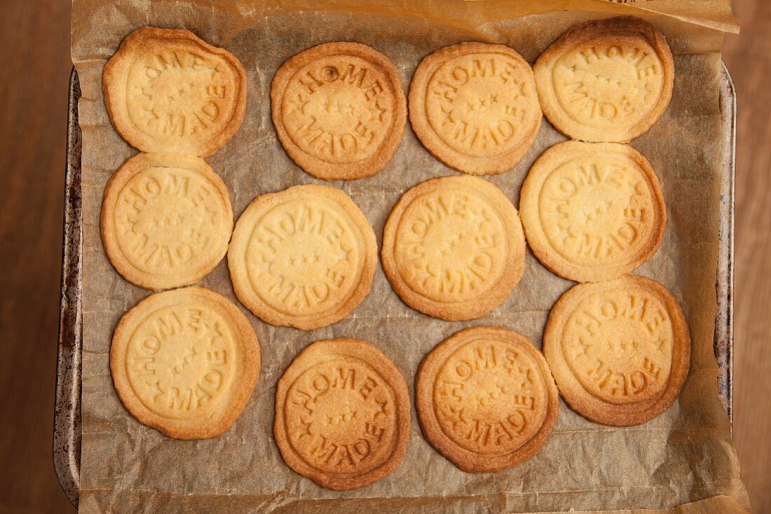 Biscuits stamped with 'home made', on a baking tray (view from above)
