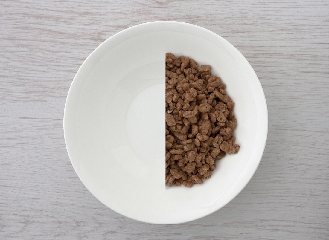 A halved portion of chocolate crisped rice in a white bowl (view from above)