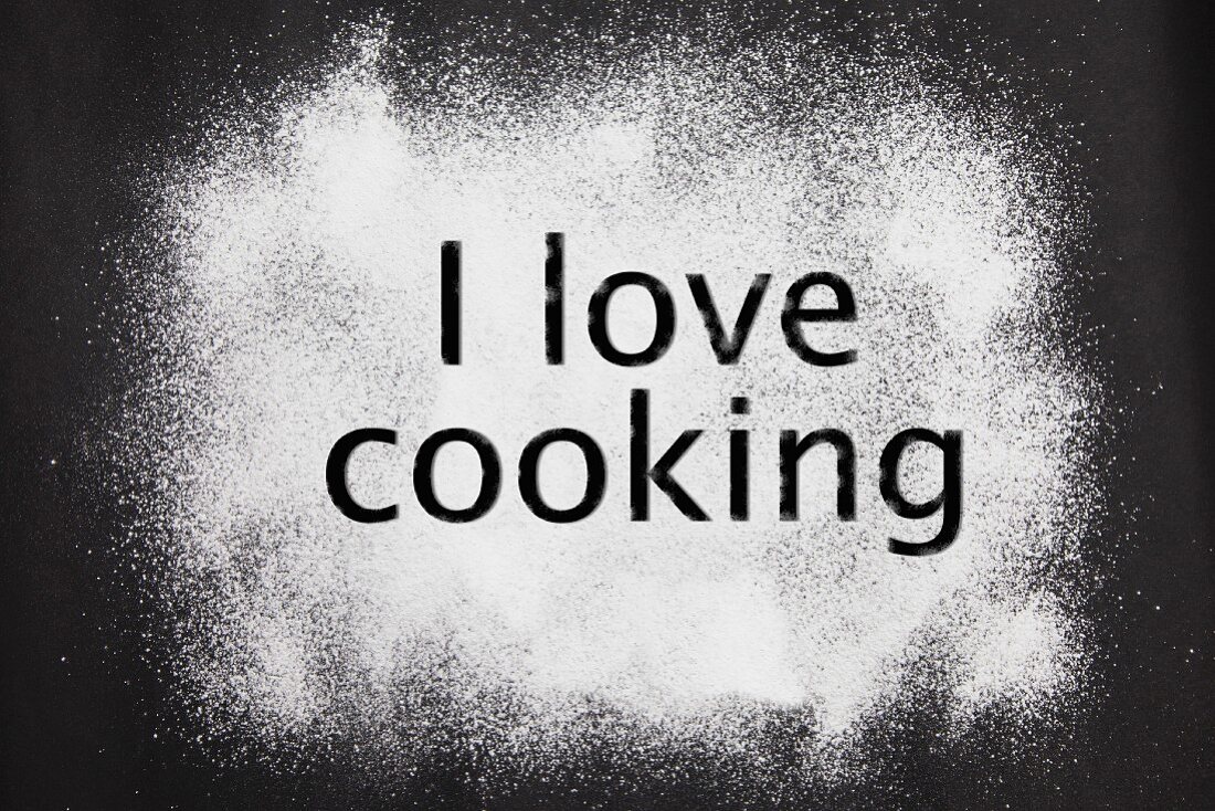 'I love cooking' etched in icing sugar on a black background