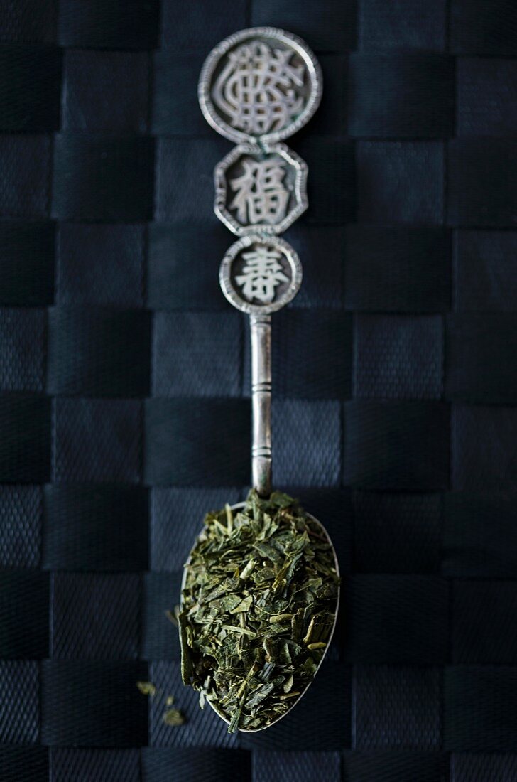 Sencha tea leaves on an Oriental silver spoon