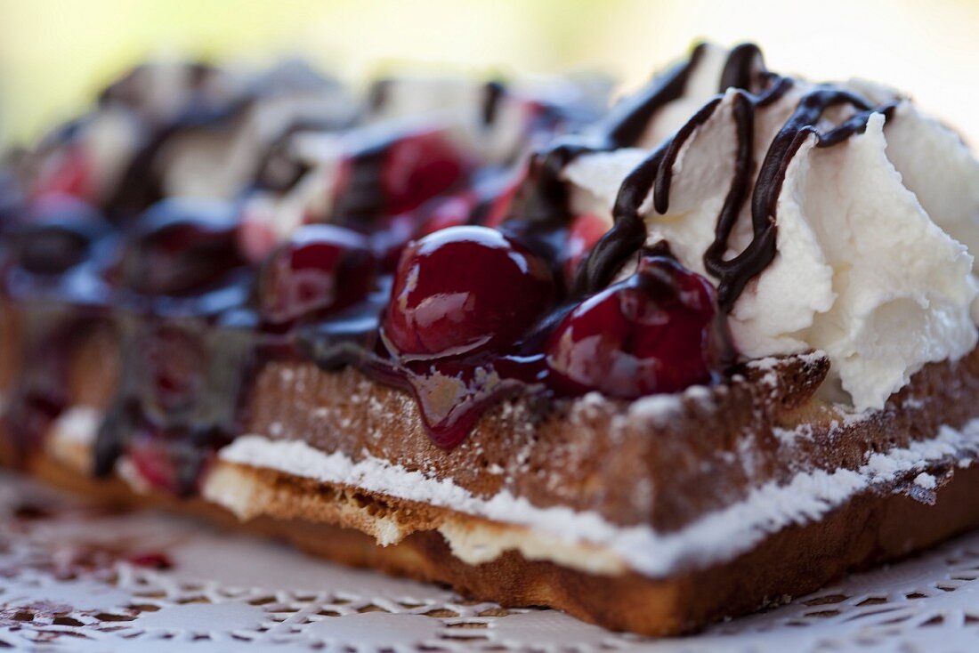 Frische Waffeln mit Kirschen, Sahne und Schokolade