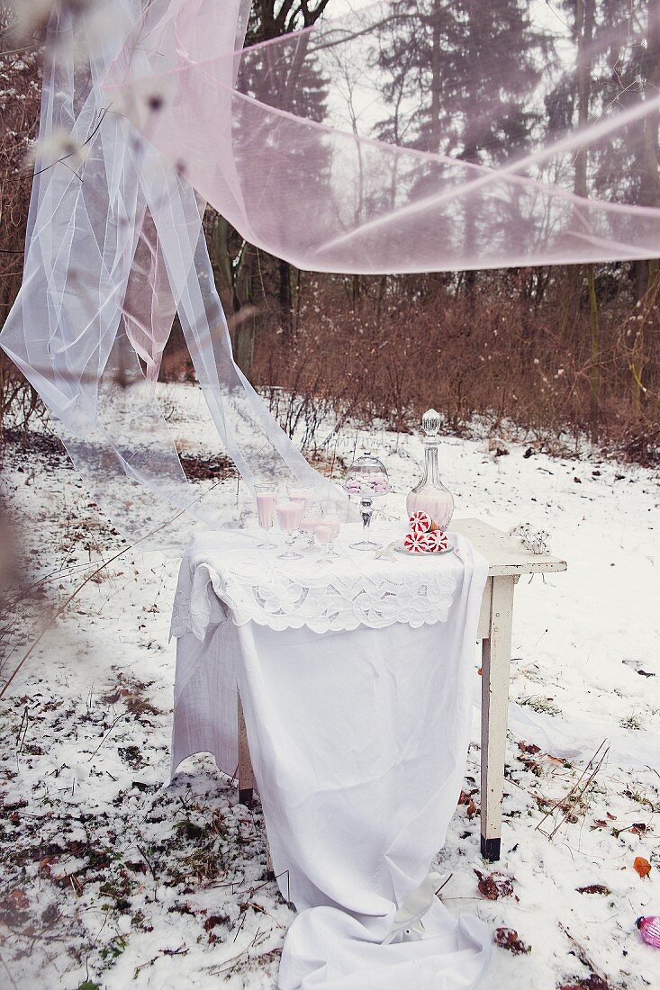 Home-made raspberry ice-cream on white table with floor-length table cloth below fluttering chiffon drapes