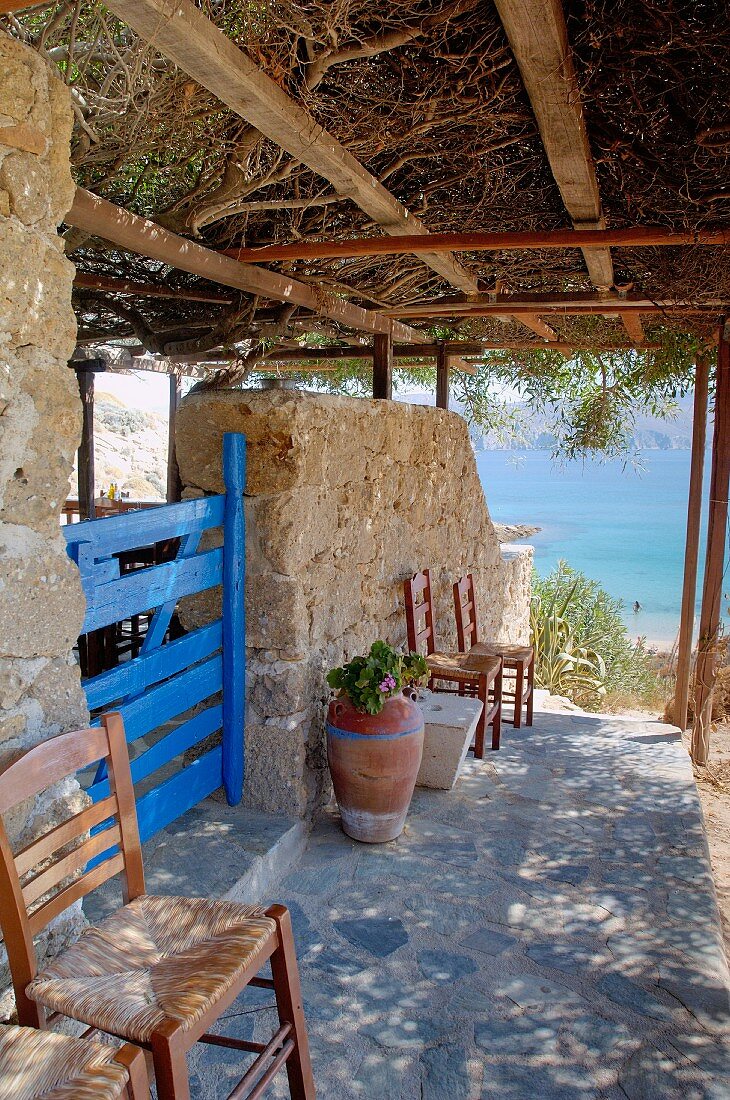 Dicht bewachsene Pergola über Natursteinweg am Haus und Blick auf das Meer