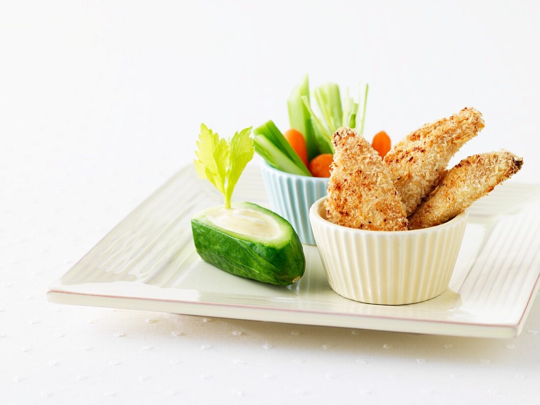 Chicken fingers (breaded chicken fillets) and crudités with a yoghurt dip