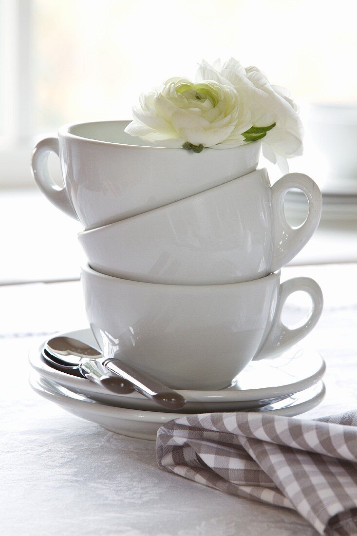 Gestapelte Kaffeetassen mit weisser Blütendekoration