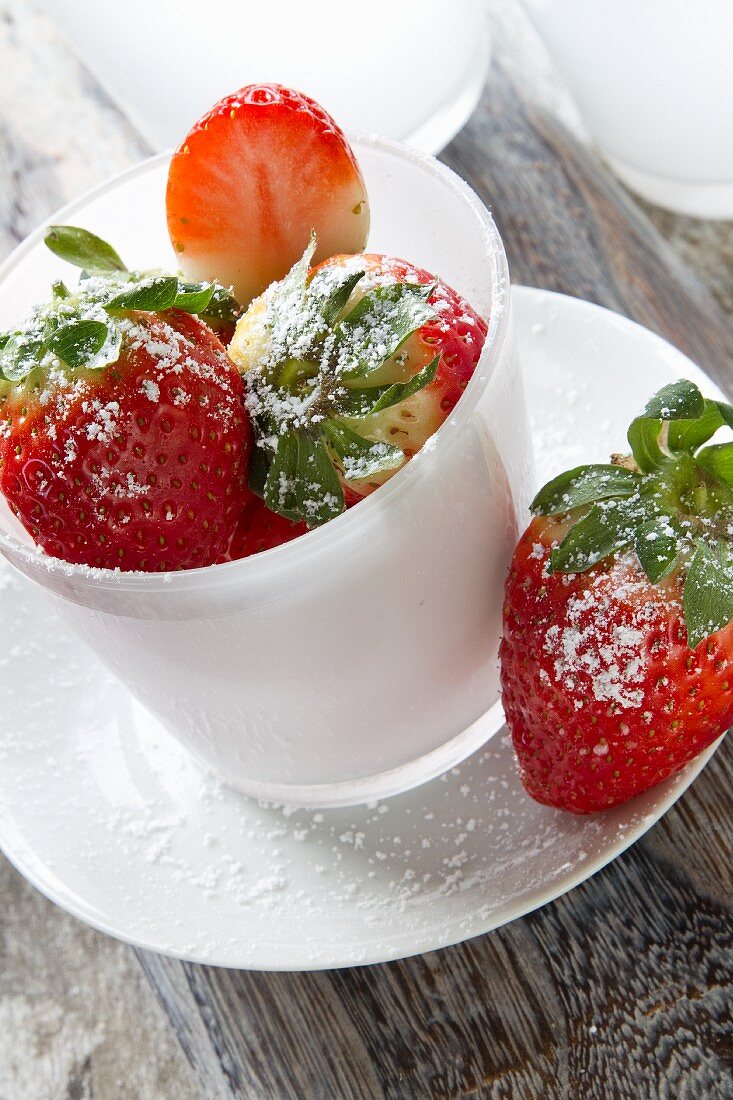 Erdbeeren mit Puderzucker in weisser Tasse