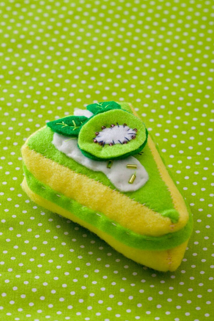 A fabric toy shaped like a slice of kiwi tart