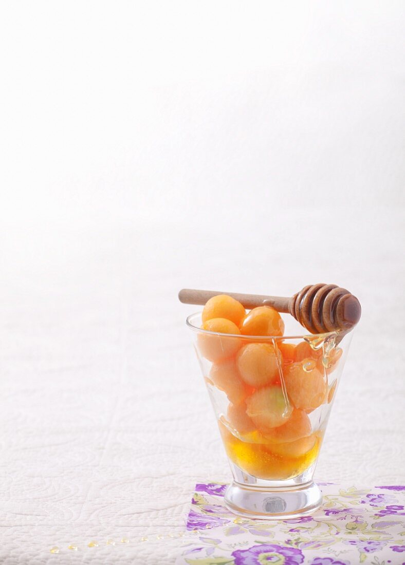 Melonenkugeln mit Honig in einem Glas