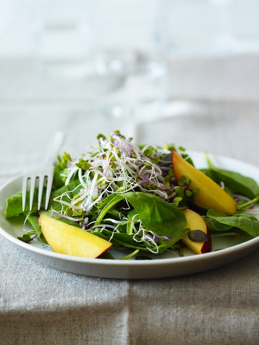 Spinach salad with edible shoots and fruit