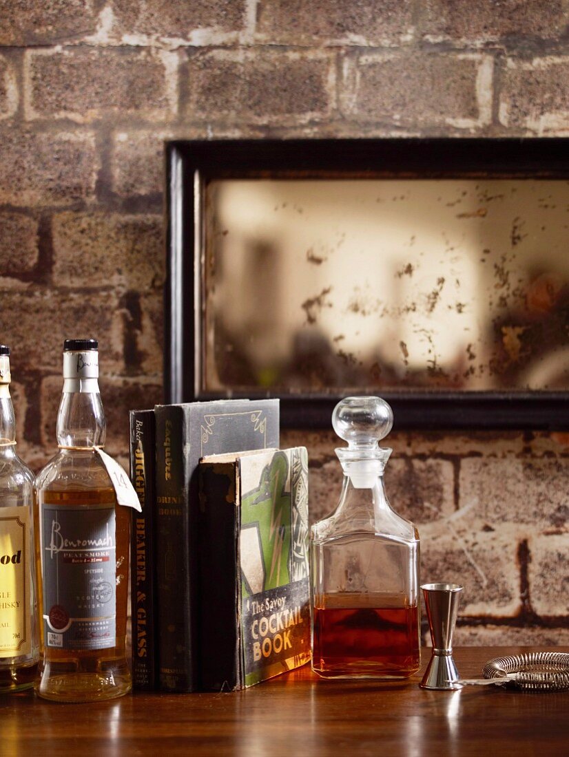 Verschiedene Whiskysorten auf Holztheke vor rustikaler Wand