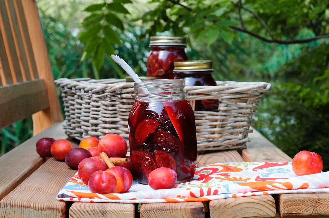Rum-soaked plums in preserving jars on a table in the garden