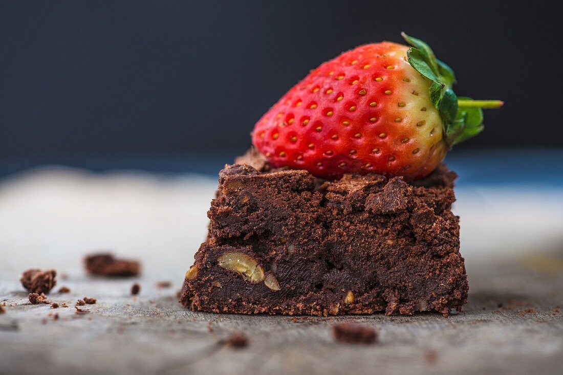 A brownie topped with a fresh strawberry