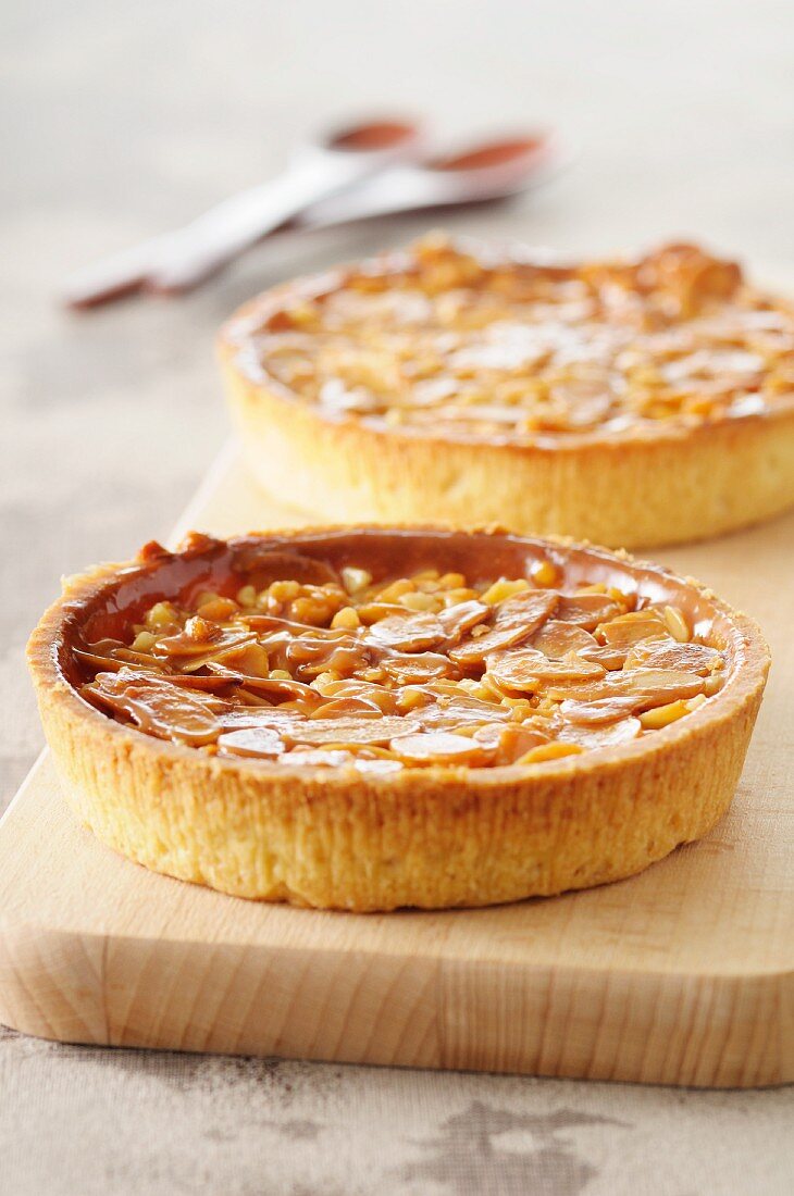 Two almond tartlets on a chopping board