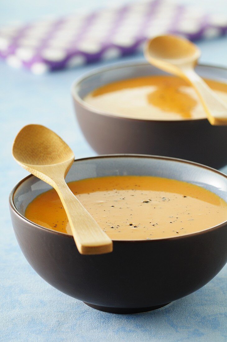 Kürbissuppe in zwei Schalen mit Holzlöffeln