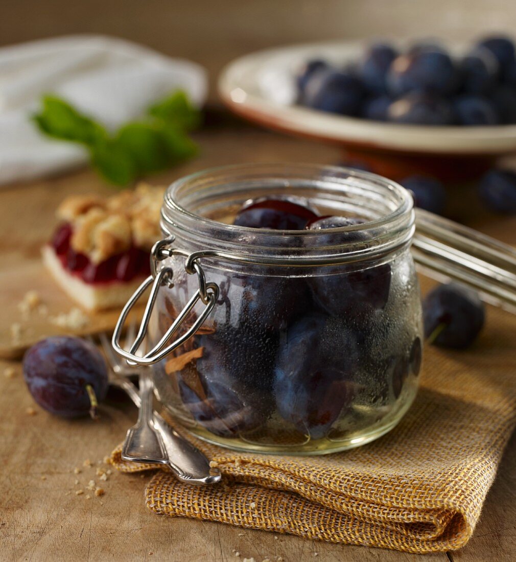 Fresh plums in an open preserving jar