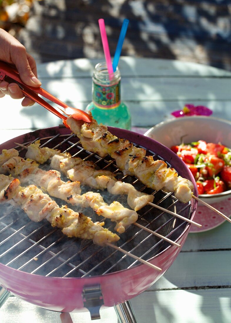 Chicken breast kebabs on the grill and a strawberry and spring onion salad