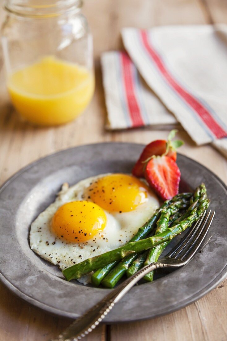 Two Fried Eggs with Sauteed Asparagus and Strawberries; Orange Juice in a Mason Jar