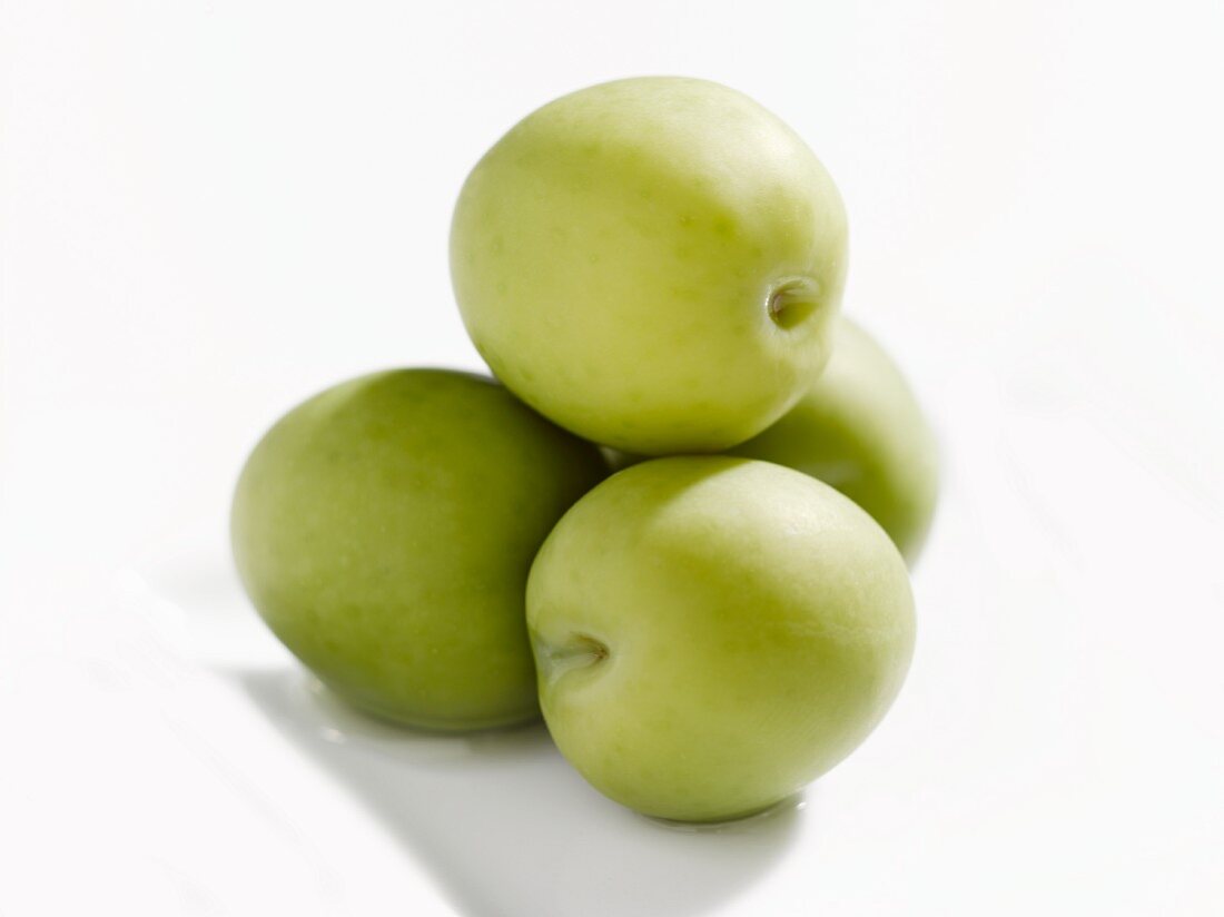 Four Stacked Green Olives on a White Dish